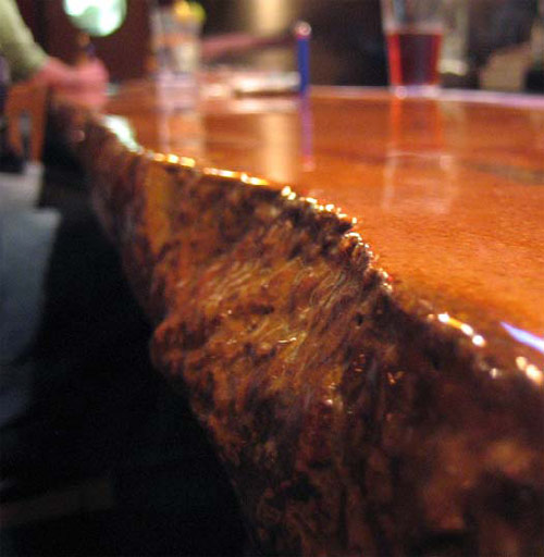 This 26-foot-long cast-in-place bar looked like a "Flintstone bar" at first, according to artisan Michael Crane. It came out with broken edges and a pale orange tone that wasn't quite right. He ground it, leaving color in recessed areas, and finished with a two-part epoxy.