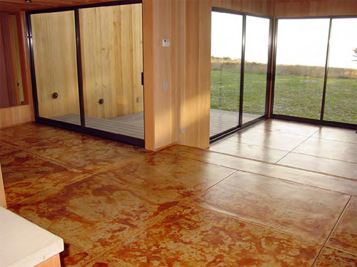 Sliding doors lead from the stained concrete floor out to a grassy space.