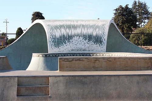 A skatepark that has been customized with a wave-like full pipe made of concrete.