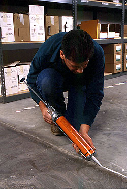 Filling a control joint with joint sealer and and orange caulking gun