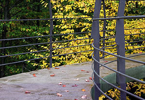 The elevated pathway that leads to the concrete treehouse is lined with metal handrails.