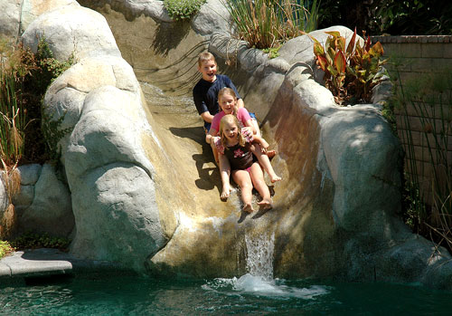 Kids sliding down a concrete waterslide.